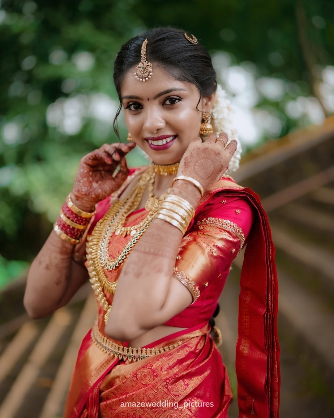 A bride in red traditional wedding attire adjusting her jewellery