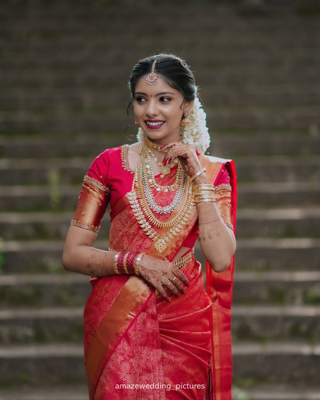 A bride in red traditional wedding attire posing on stone steps